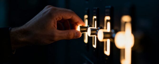 Hand reaching for glowing levers in the dark.